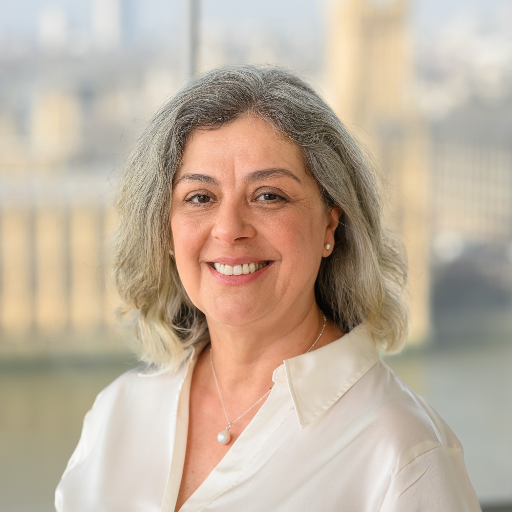 Miss Gabriella Gray consultant obstetrician, smiling woman standing in front of background of houses of parliament and Big Ben.