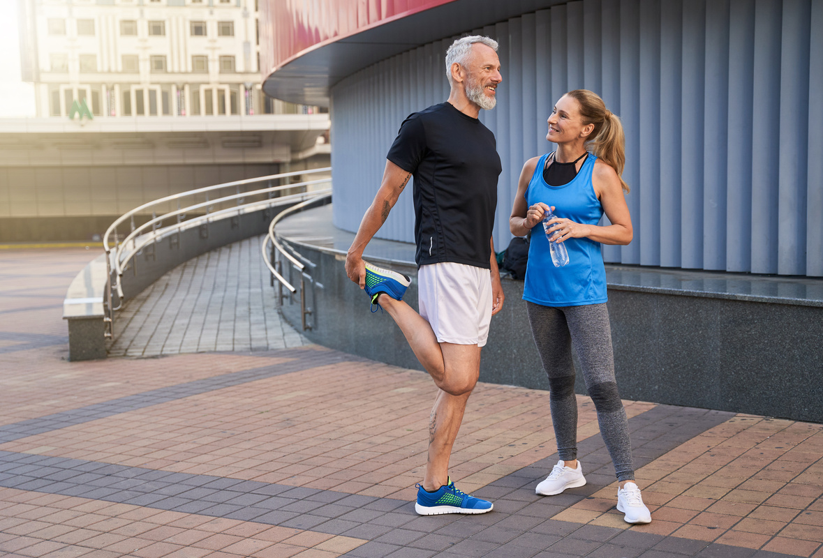 Happy man and woman in sportswear smiling while outside