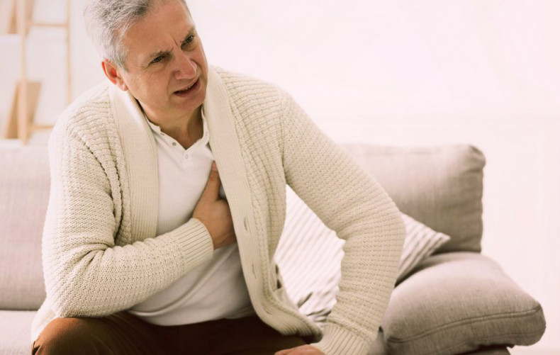 Man on sofa with right hand over heart