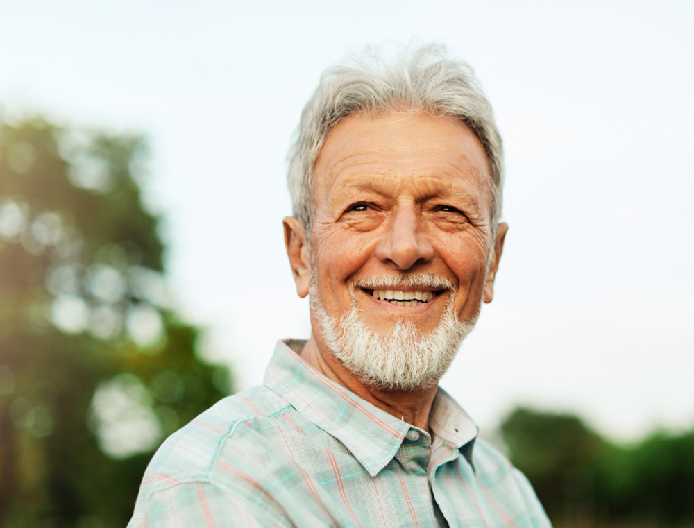 Close up of a smiling older man outdoors.