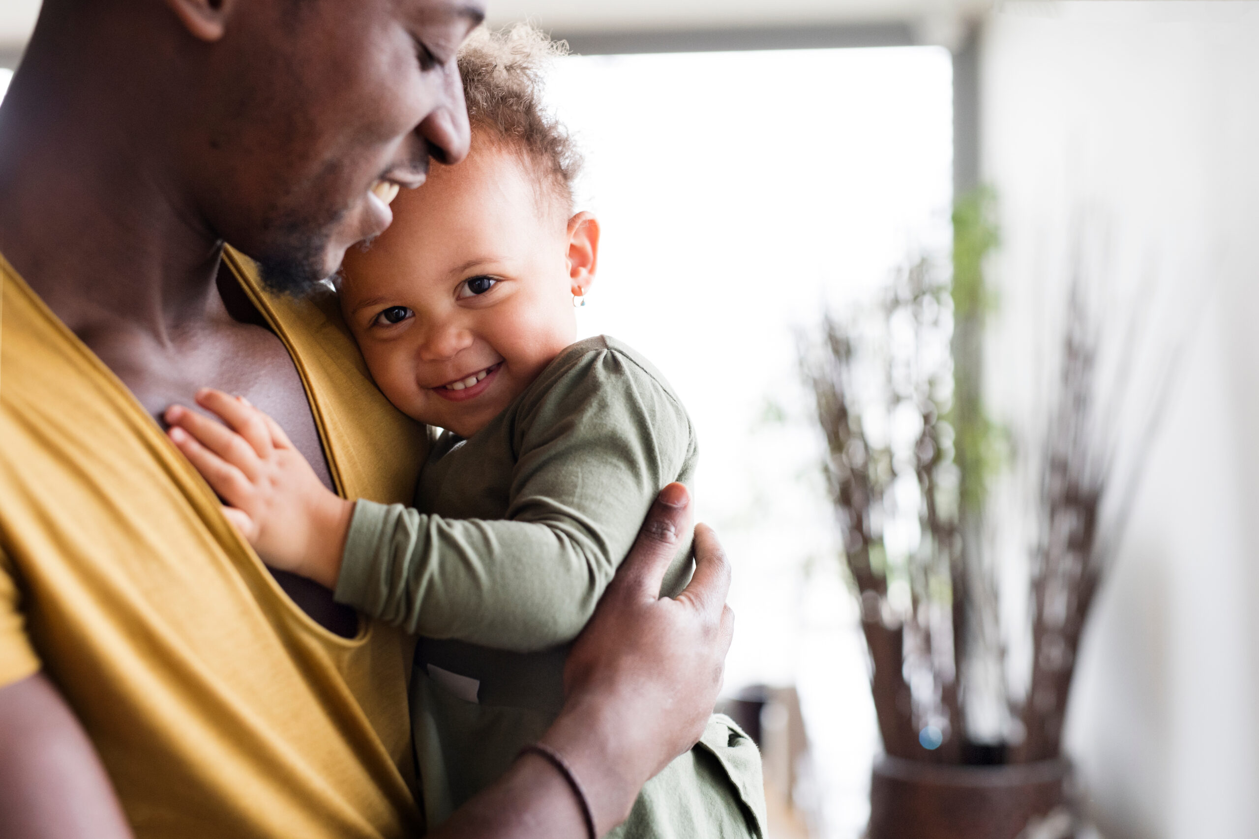 Father holding daughter cuddled, with both smiling