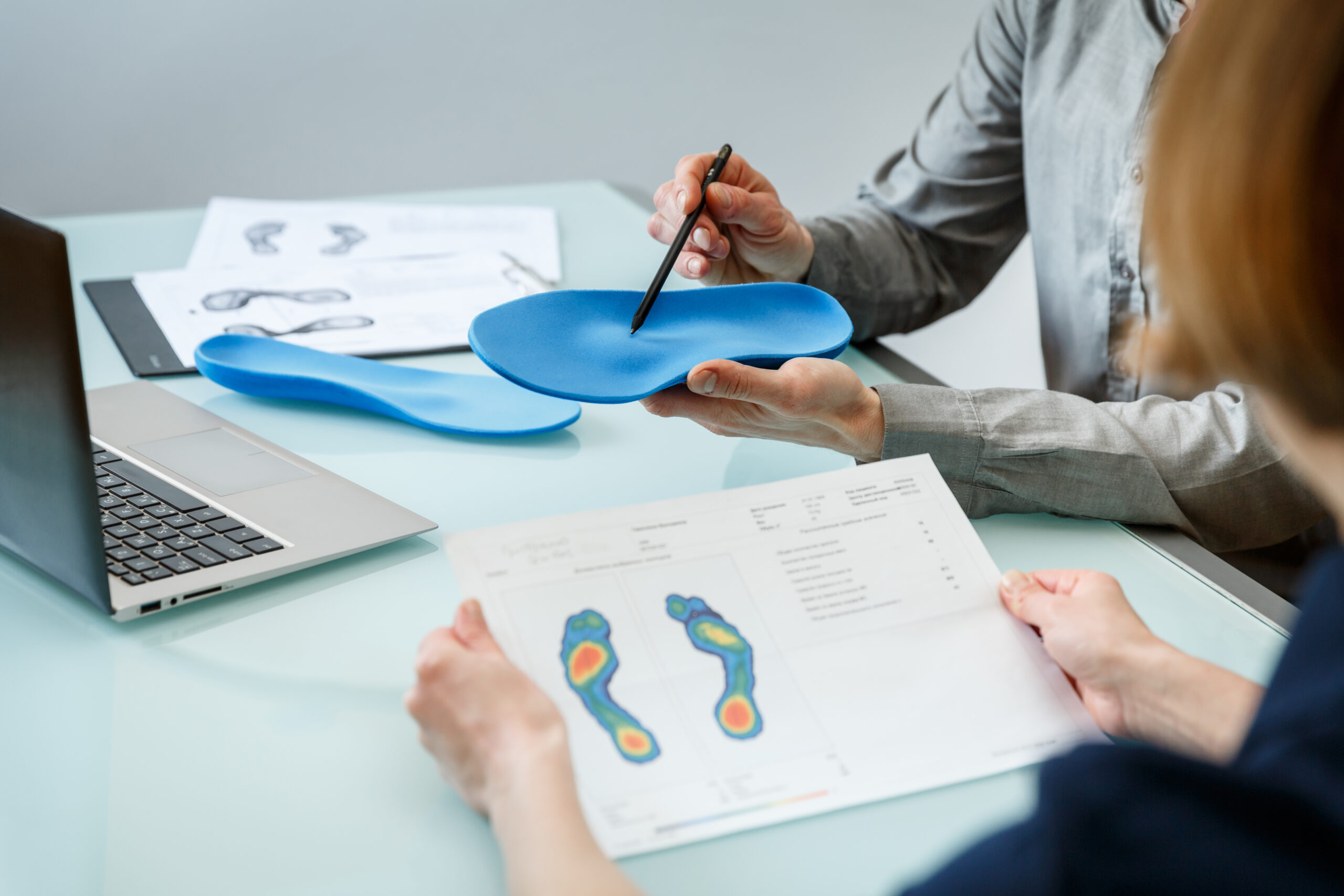 Doctor consulting patient on custom orthotic insoles in a clinic for a personalised custom fit.