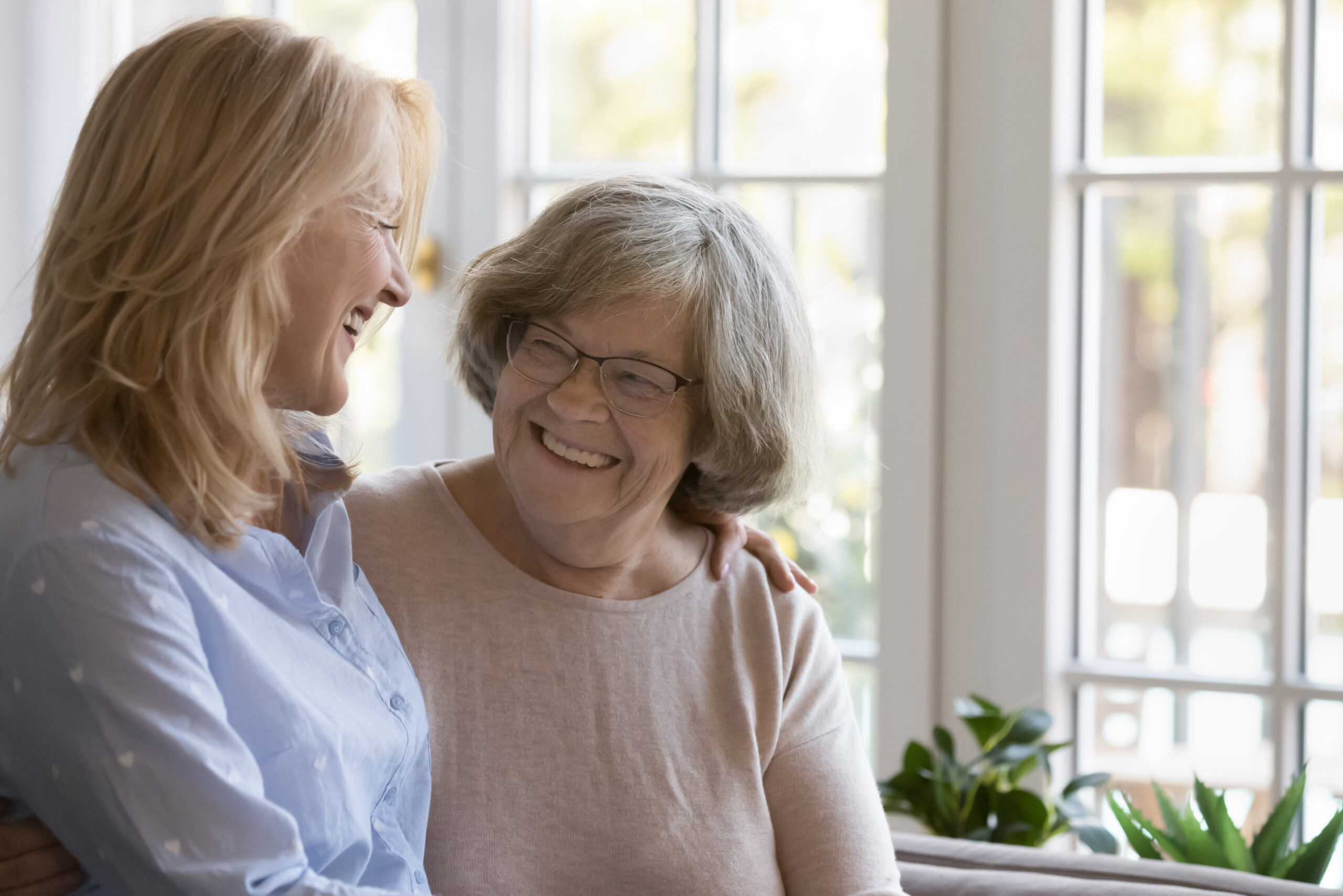 Caring middle-aged woman hugging her senior grey-haired mother