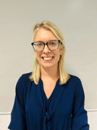 Blonde haired woman wearing glasses smiling for headshot.