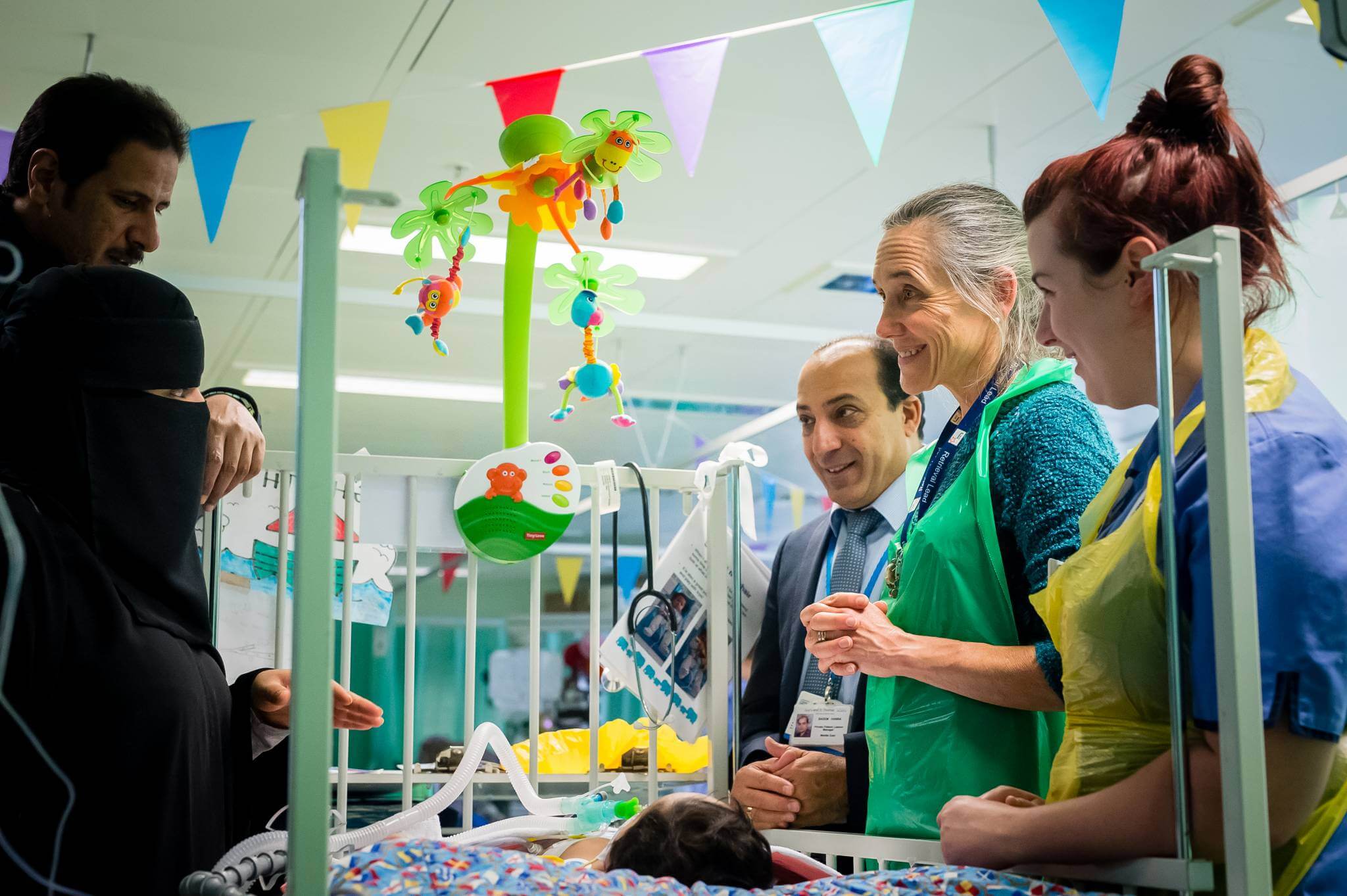 Smiling consultants and nurses helping baby in Sky ward at Evelina London