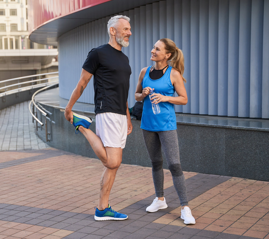 Happy man and woman in sportswear smiling while outside