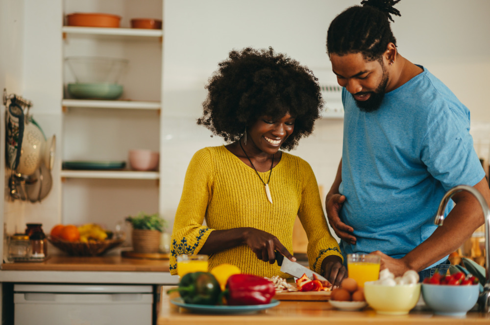 A happy couple is cooking dinner together at home.