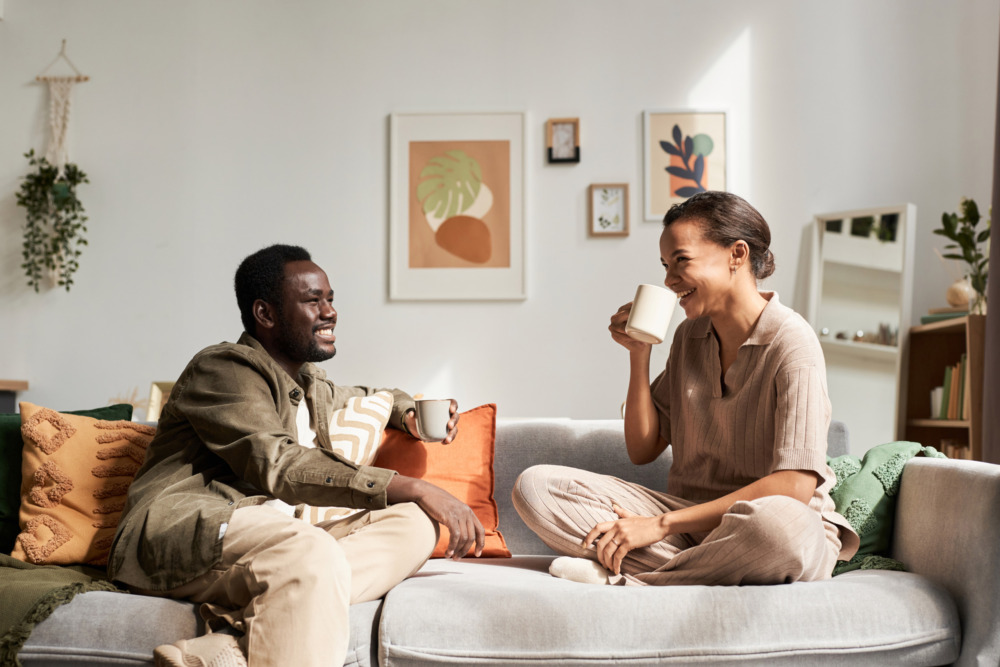 Young couple enjoying conversation sitting on a sofa and laughing in a cosy home