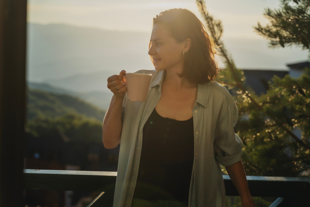 Young woman greeting the morning at dawn standing on a balcony overlooking the mountains