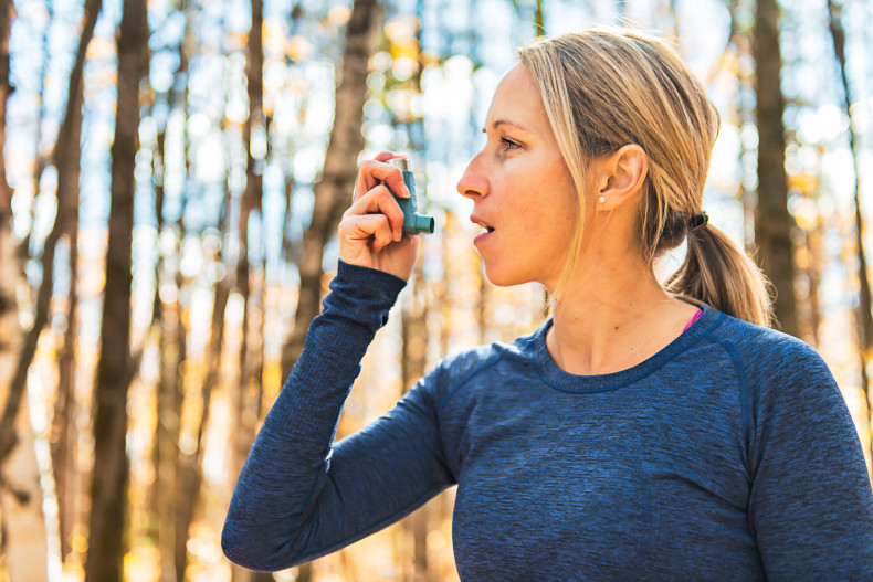 woman uses blue inhaler for asthma