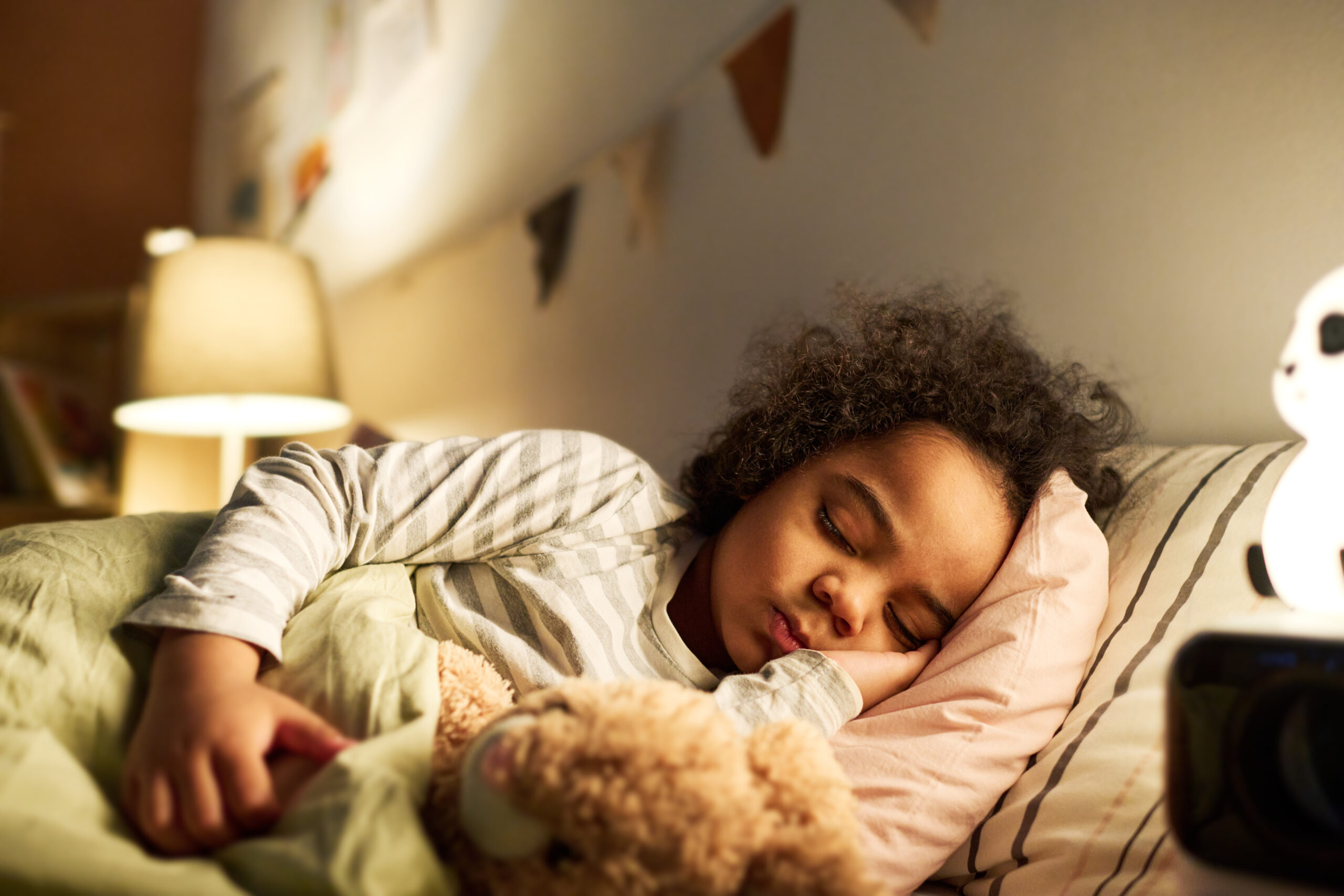 Little boy sleeping in bed with toy