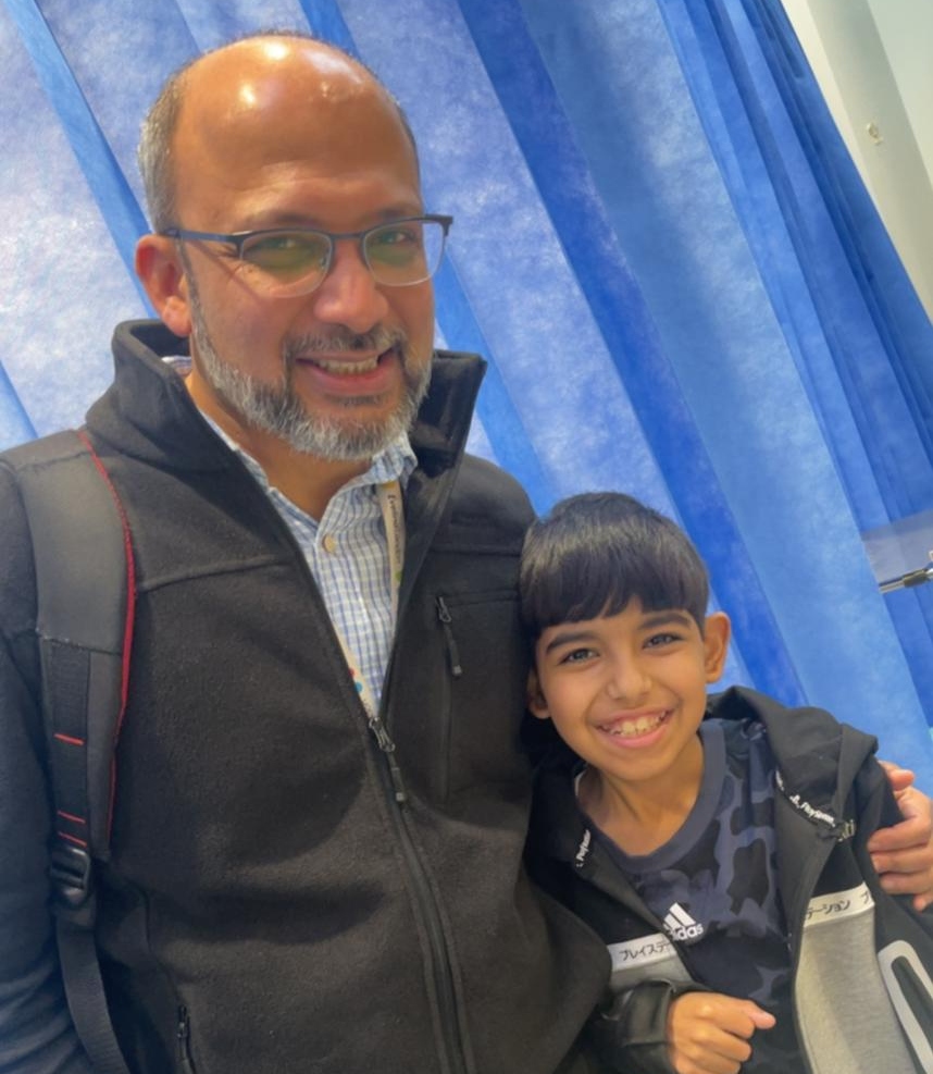 Smiling man wearing glasses holding smiling, brunette boy